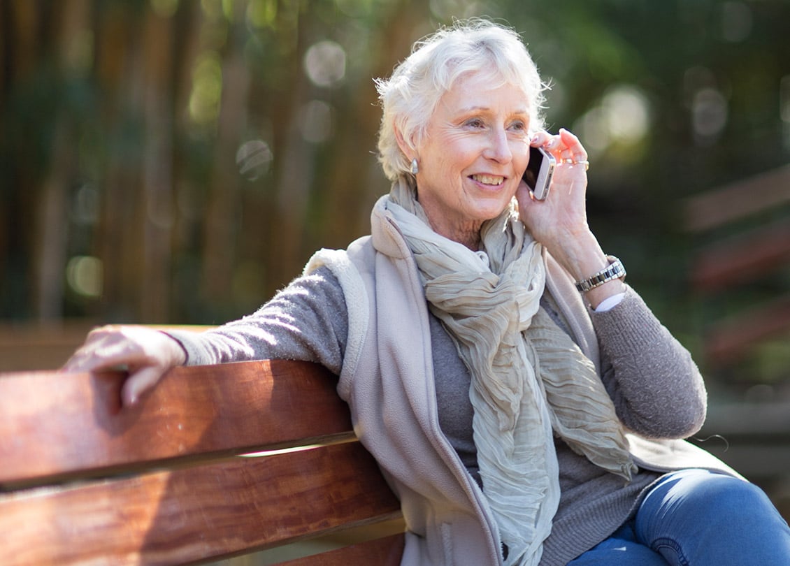 Image of woman – Jakafi patient – talking on the phone, sitting on a park bench