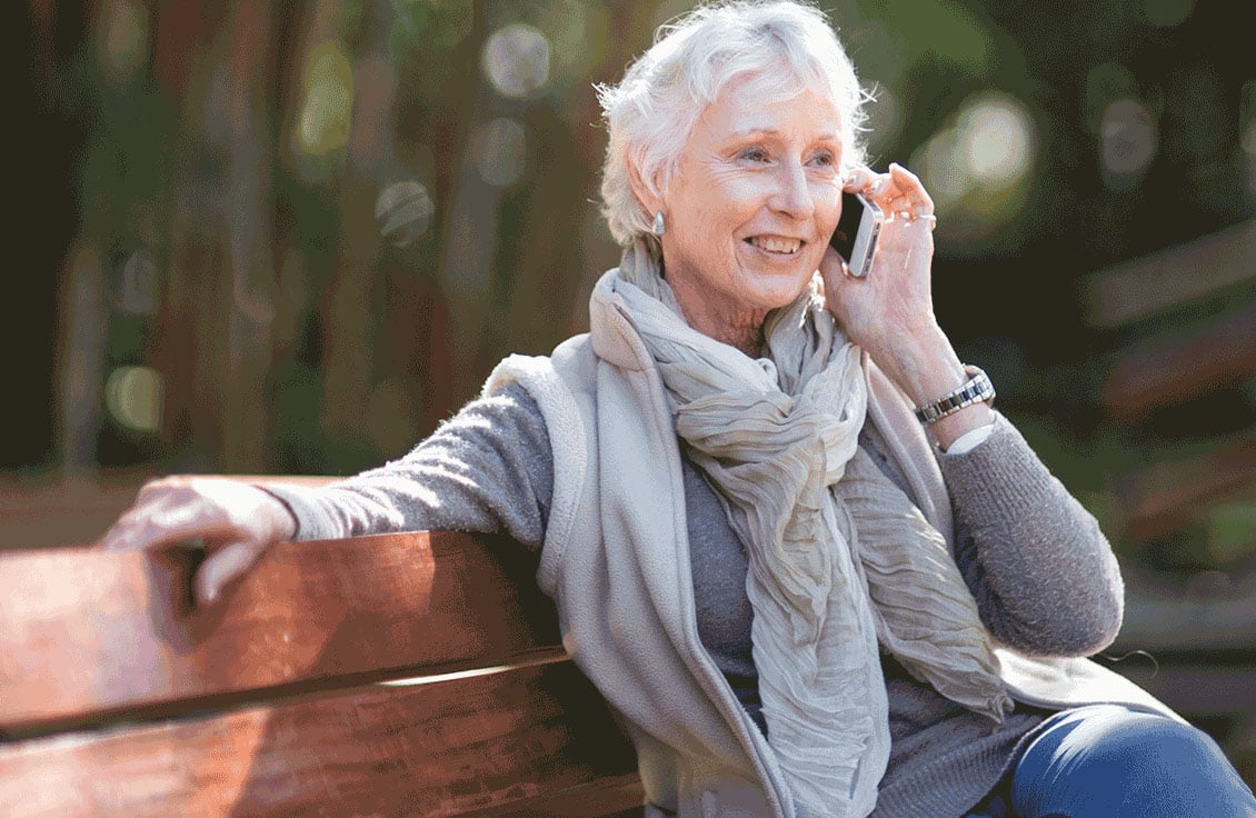 Image of woman – Jakafi patient – talking on the phone, sitting on a park bench